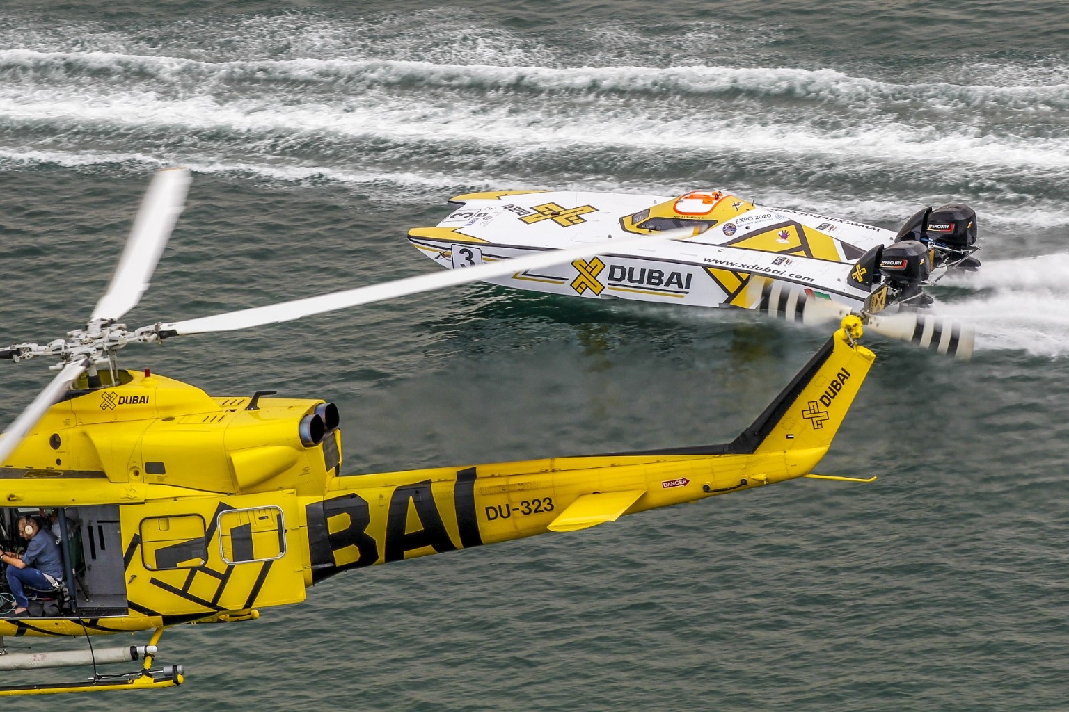 Yellow helicopter following an offshore powerboat